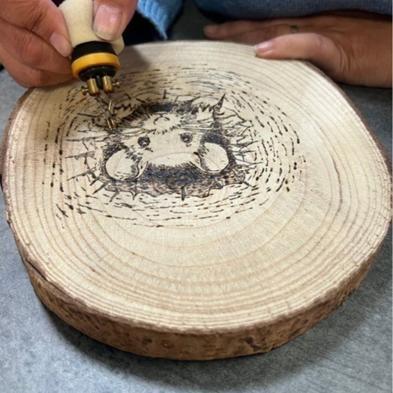 Houtbranden op boomstamschijf tijdens Kreadoe. Patroon met muis.